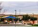 A playground with a blue sunshade is surrounded by lush landscaping, providing a welcoming community space at 132 Soaring Sky Ave, Henderson, NV 89011