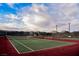 A vibrant red and green tennis court with a high fence offers recreational opportunities and a scenic skyline at 132 Soaring Sky Ave, Henderson, NV 89011
