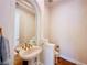 Stylish powder room featuring an elegant pedestal sink, gold fixtures, and arched mirror at 2017 Eagle Trace Way, Las Vegas, NV 89117