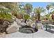 In-ground hot tub surrounded by rock features, palm trees, and lush landscaping at 2222 Lucerne Ct, Henderson, NV 89014