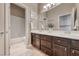 Spacious bathroom featuring double sinks, dark wood cabinetry, and a shower-tub combo at 2544 Ashley Rose Ter, Henderson, NV 89052