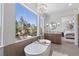 Bright bathroom with soaking tub, chandelier, and large window with scenic views at 276 Glenridding St, Las Vegas, NV 89183