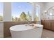 Bathroom featuring a soaking tub, wooden vanity, and large window overlooking trees at 276 Glenridding St, Las Vegas, NV 89183
