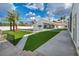 A backyard featuring green artificial turf, a pool, and palm trees creates a stunning outdoor oasis at 3630 Tobias Ln, Las Vegas, NV 89120