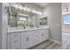 Bright bathroom features double sinks with white cabinets, a large mirror and modern lighting at 4781 Stoneham, Pahrump, NV 89061