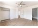 Bright bedroom with light wood floors, ceiling fan, and open closet, leading to bathroom with tiled shower at 5751 Mabel Rd, Las Vegas, NV 89110