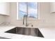 Close-up of kitchen sink area featuring stainless steel sink, designer faucet, white countertop, and bright window view at 5751 Mabel Rd, Las Vegas, NV 89110
