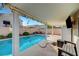 A covered outdoor space is equipped with a TV, refrigerator, and seating to complement this home's refreshing pool at 5823 Rose Sage St, North Las Vegas, NV 89031