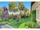 Serene backyard featuring manicured lawn, mature trees, privacy landscaping, and garden beds at 748 Puerto Real Ct, Las Vegas, NV 89138