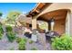 Backyard with covered outdoor living area with fireplace, dining area, pool, and lush landscaping at 748 Puerto Real Ct, Las Vegas, NV 89138