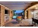Elegant covered patio features a stone fireplace, ceiling fan, and overlooks the pool and spa at 748 Puerto Real Ct, Las Vegas, NV 89138