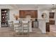 Home bar features seating for three, dark wood cabinetry, and stainless steel beverage refrigerator at 748 Puerto Real Ct, Las Vegas, NV 89138