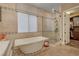 Soaking tub and glass enclosed shower featuring decorative tiles and neutral color pallette at 748 Puerto Real Ct, Las Vegas, NV 89138