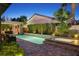 Outdoor pool and spa with beautiful patio, bar, and landscaping at dusk at 748 Puerto Real Ct, Las Vegas, NV 89138