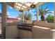Built in outdoor grill with lighting fixture in covered outdoor space and mature landscaping at 8000 Vista Twilight Dr, Las Vegas, NV 89123
