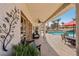 Charming covered patio with comfortable seating and a view of the pool and landscaped backyard at 8104 Wispy Sage Way, Las Vegas, NV 89149