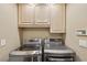 Bright laundry room features cabinets and modern, front loading washer and dryer at 8104 Wispy Sage Way, Las Vegas, NV 89149