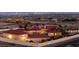 Expansive home with red tile roof, lush palm trees and desert landscape at dusk with city views at 10280 W La Mancha Ave, Las Vegas, NV 89149