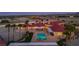 Expansive home with red tile roof, lush palm trees, sparkling pool and beautiful desert landscape at dusk at 10280 W La Mancha Ave, Las Vegas, NV 89149