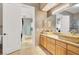 Modern bathroom featuring double sinks, light wood cabinets, and open doorway at 10280 W La Mancha Ave, Las Vegas, NV 89149