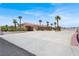 Wide driveway leads to a beautiful home with palm trees and a red tile roof under a clear blue sky at 10280 W La Mancha Ave, Las Vegas, NV 89149