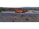 Twilight view of an estate with red tile roof, palm trees and perimeter lighting for enhanced curb appeal at 10280 W La Mancha Ave, Las Vegas, NV 89149
