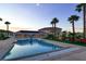 A beautiful in-ground pool at dusk, set against a large backyard with tropical palm trees at 10280 W La Mancha Ave, Las Vegas, NV 89149