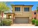 Two-story tan home featuring a two-car garage and stone accents under a blue sky at 10805 Cain Ave, Las Vegas, NV 89166