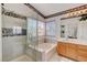 Elegant bathroom featuring a tiled glass shower, soaking tub, wood vanity and windows providing plenty of light at 1333 Date Palm Cir, Las Vegas, NV 89108