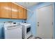 Functional laundry room with wood cabinets above the washing machine and dryer, and access to the outside at 1333 Date Palm Cir, Las Vegas, NV 89108