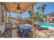 Outdoor kitchen, dining and lounging patio with ceiling fan and view of pool and desert landscaping at 1701 Drifters Peak St, Las Vegas, NV 89144
