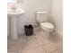 A well-lit bathroom featuring a pedestal sink, toilet, and neutral tile flooring at 1703 Game Garden Rd, North Las Vegas, NV 89031