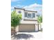 Inviting two-story home featuring a tan exterior, a two-car garage and a lovely tree in the front yard at 1703 Game Garden Rd, North Las Vegas, NV 89031