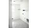 Bright laundry room with gray tile, storage shelf, and washer/dryer hookups at 1703 Game Garden Rd, North Las Vegas, NV 89031