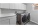 Bright laundry room with modern washer and dryer, white cabinets, counter space, and window at 2231 Desert Prairie St, Las Vegas, NV 89135