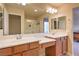 Bright bathroom features double sinks, wood cabinets, and shower over bath at 2373 Rue Royale St, Henderson, NV 89044