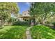 Grassy backyard with covered patio, mature trees, and stone walkway at 2412 Muirfield Ave, Henderson, NV 89074