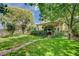 Expansive backyard with green lawn, mature trees, and a covered patio with garden archway at 2412 Muirfield Ave, Henderson, NV 89074