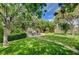 Lush green backyard featuring a stone patio dining area and mature landscaping at 2412 Muirfield Ave, Henderson, NV 89074