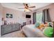 This bedroom features light pink walls, carpet flooring, a ceiling fan, and a bed with many throw pillows at 2412 Muirfield Ave, Henderson, NV 89074