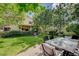 Large backyard with green lawn, patio dining area and mature trees at 2412 Muirfield Ave, Henderson, NV 89074