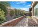 Landscaped backyard showcasing a retaining wall with trees, flowers, and desert scape at 2771 Free Formed Ct, Las Vegas, NV 89138