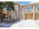 Charming stucco townhouse with a two-car garage, beautiful arched windows, and desert landscaping at 2830 Crystal Lantern Dr, Henderson, NV 89074