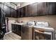 This laundry room features dark wood cabinets, a white counter top, and a modern washer and dryer at 2896 Grande Arch St, Henderson, NV 89044
