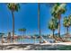 Sandy community beach with lounge chairs under palm trees and clear blue skies at 2904 Channel Bay Dr, Las Vegas, NV 89128