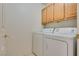 Convenient laundry room features wood cabinets above the washer and dryer for streamlined functionality at 2904 Channel Bay Dr, Las Vegas, NV 89128