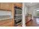 Modern kitchen with stainless steel double ovens and granite countertops and wood cabinets at 3728 White Lion Ln, North Las Vegas, NV 89084