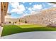 Backyard featuring artificial grass, rock landscaping, and secure rock wall fence at 3811 Queen Elizabeth Ct, Laughlin, NV 89029