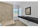 Modern bathroom with vessel sink, black vanity, and a stone tiled shower at 4016 Owlshead Mountain St, Las Vegas, NV 89129