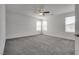 This primary bedroom has neutral carpet, three windows, and a ceiling fan at 4448 Mahogany Hills Ave, Las Vegas, NV 89141